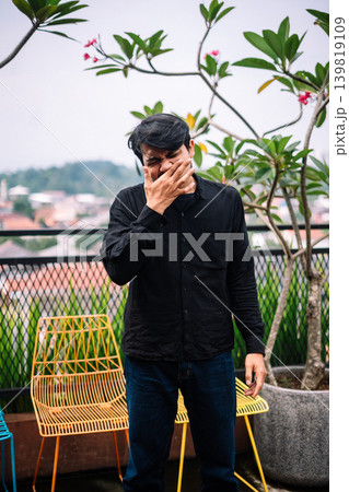 Southeast Asian man rubbing itchy nose outdoors 139819109