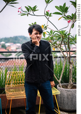 Southeast Asian man suffering from toothache outdoors Southeast Asian man suffering from toothache outdoors 139819111