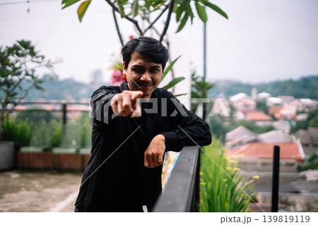 Southeast Asian man pointing toward camera outdoors Southeast Asian man pointing toward camera outdoors 139819119