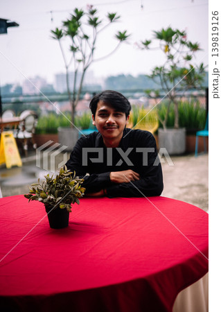 Southeast Asian man sitting alone at red round reception table outdoors Southeast Asian man sitting alone at red round reception table outdoors 139819126