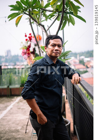 Asian man relaxing on urban rooftop balcony with cityscape Asian man relaxing on urban rooftop balcony with cityscape 139819145