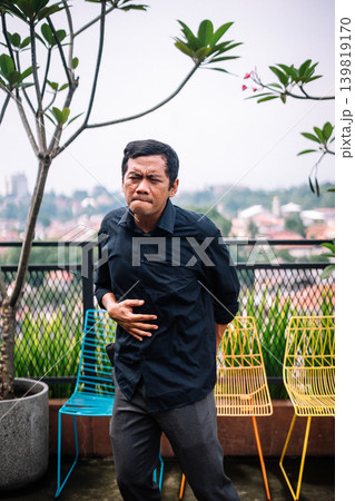 Man Suffering From Stomach Pain and Discomfort Outdoors Man Suffering From Stomach Pain and Discomfort Outdoors 139819170