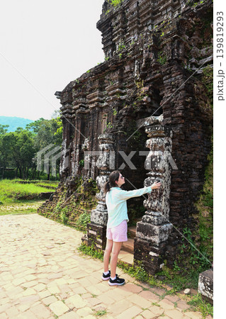 A 30 year old Russian woman tourist touches an ancient stone pillar at My Son sanctuary ruins near Da Nang city in Quang Nam province Vietnam 139819293