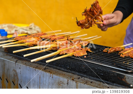 A street vendor grills traditional Vietnamese Thit Nuong pork skewers on bamboo sticks at an outdoor food stall in Hoi An Vietnam A street vendor grills traditional Vietnamese Thit Nuong pork skewers on bamboo sticks at an outdoor food stall in Hoi An Vietnam 139819308