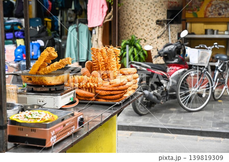 A variety of Vietnamese street food snacks including tornado potatoes and banh mi are displayed at an outdoor food stall in Hoi An Vietnam A variety of Vietnamese street food snacks including tornado potatoes and banh mi are displayed at an outdoor food stall in Hoi An Vietnam 139819309