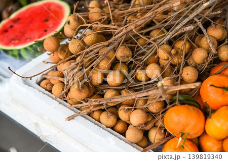 A close up view of fresh tropical qua nhan longan fruit on branch displayed at a traditional street fruit market stall in Hoi An Vietnam A close up view of fresh tropical qua nhan longan fruit on branch displayed at a traditional street fruit market stall in Hoi An Vietnam 139819340