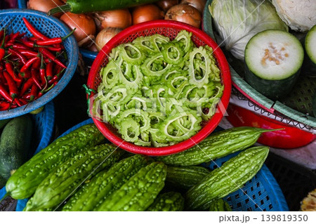 A close up top view of fresh green bitter melon slices and whole bitter gourds displayed at a traditional street vegetable market in Vietnam 139819350