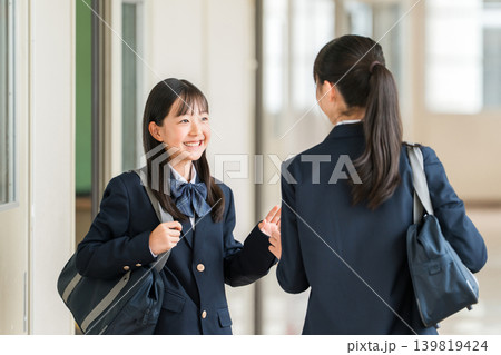 学校の廊下を歩く制服姿の小学生,中学生,高校生の女子生徒 139819424