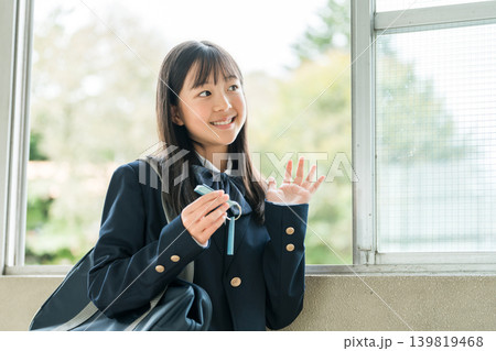 学校の廊下で単語帳を見ながら勉強するブレザー姿の女の子 学校の廊下で単語帳を見ながら勉強するブレザー姿の女の子 139819468