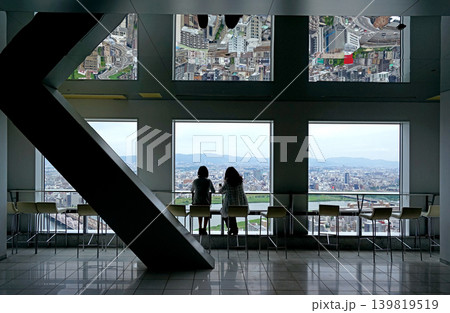 Two people enjoying panoramic Japan Osaka city view from high rise observation deck with mirrored ceiling 139819519