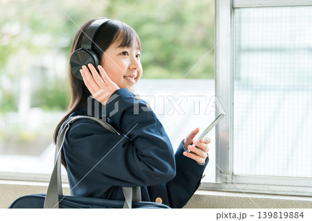 学校の廊下でヘッドフォンで音楽を聴く制服姿の小学生,中学生,高校生の女の子 学校の廊下でヘッドフォンで音楽を聴く制服姿の小学生,中学生,高校生の女の子 139819884