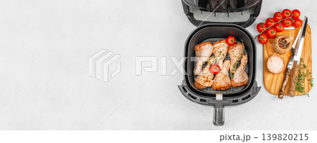 Air fryer chicken drumsticks with spices and tomatoes, top view healthy cooking background with copy space 139820215