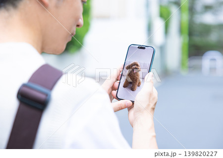 ペット　外出先でペットカメラに接続して愛犬の様子をチェックする飼い主の手元 139820227
