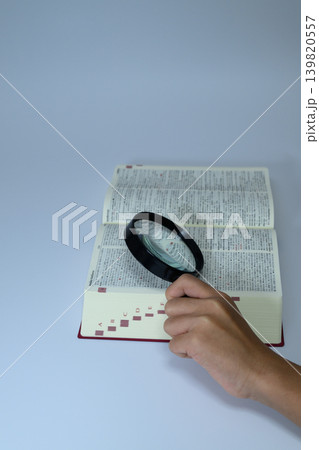 虫眼鏡で辞書を調べる人の手元 虫眼鏡で辞書を調べる人の手元 139820557