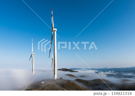 青空と雲海が広がる山頂にそびえ立つ風力発電の風車と自然風景 青空と雲海が広がる山頂にそびえ立つ風力発電の風車と自然風景 139821319