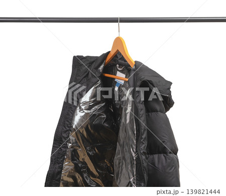 Black winter jacket hanging on wooden hanger. Insulated outerwear with silver thermal lining. Vintage menswear coat suggesting thrift or secondhand clothing.. Black winter jacket hanging on wooden hanger. Insulated outerwear with silver thermal lining. Vintage menswear coat suggesting thrift or secondhand clothing.. 139821444