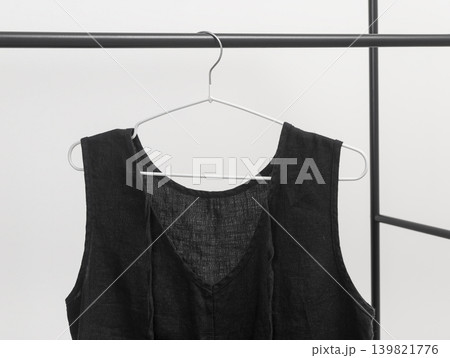 Black summer clothes, dress hanging on nonstick hanger on metal rail, rod isolated on white background. Black summer clothes, dress hanging on nonstick hanger on metal rail, rod isolated on white background. 139821776