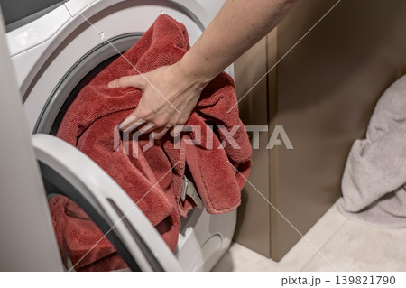 Hand loading towel closeup, placing cloth into washing machine appliance. 139821790