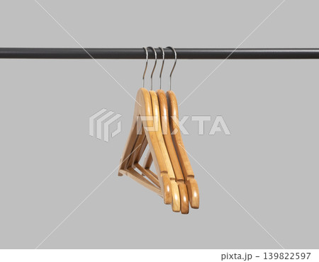 Wooden hangers stacked vertically on black metal rack. Garment holders aligned on horizontal bar. Interior organization setup for wardrobe, retail, storage concept.. Wooden hangers stacked vertically on black metal rack. Garment holders aligned on horizontal bar. Interior organization setup for wardrobe, retail, storage concept.. 139822597