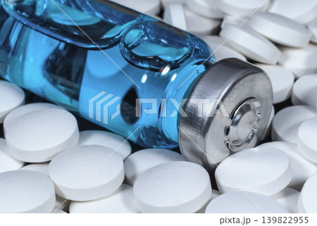 Medical bottle with blue vaccine surrounded by white pills 139822955