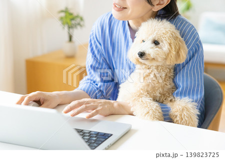 テレワーク 犬を抱っこしながら仕事をする女性 テレワーク 犬を抱っこしながら仕事をする女性 139823725