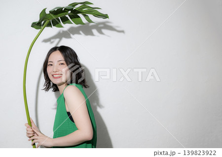 モンステラの葉を傘にするかわいい笑顔の日本人女性、傘や夏の自然のイメージカメラ目線の上半身 モンステラの葉を傘にするかわいい笑顔の日本人女性、傘や夏の自然のイメージカメラ目線の上半身 139823922