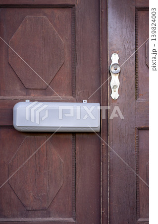 View of a mailbox for newspapers and letters hanging on a wooden door 139824003