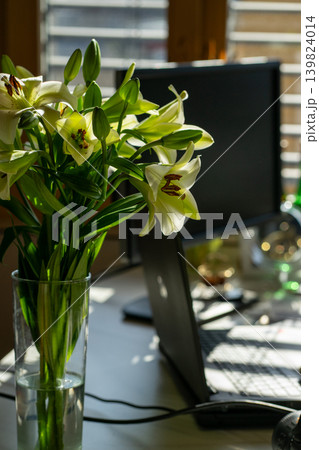 A bouquet of white lilies against the background of a working home office A bouquet of white lilies against the background of a working home office 139824014