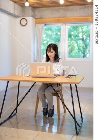 デスクでパソコン作業をする日本人の若い女性 デスクでパソコン作業をする日本人の若い女性 139824314