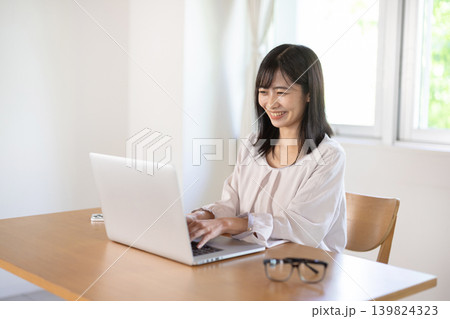 デスクでパソコン作業をする日本人の若い女性 デスクでパソコン作業をする日本人の若い女性 139824323