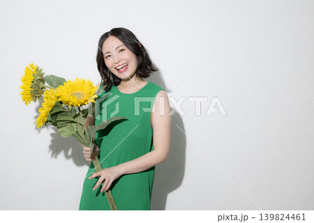 向日葵(ひまわり)を持って笑顔を見せる日本人女性の夏の美容や明るいライフスタイルカメラ目線イメージ 向日葵(ひまわり)を持って笑顔を見せる日本人女性の夏の美容や明るいライフスタイルカメラ目線イメージ 139824461