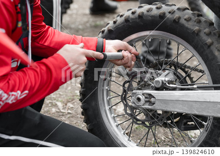 Mechanic hands adjusting spokes on a motocross bike rear wheel. Mechanic hands adjusting spokes on a motocross bike rear wheel. 139824610