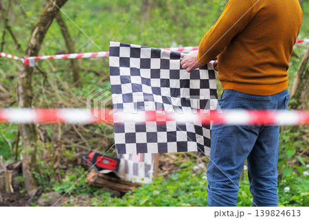 Race official holding a checkered flag at the finish line of an outdoor sports event. Success and achievement concept 139824613