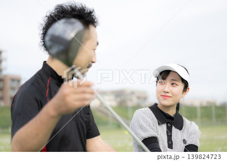 笑顔でゴルフを習う女性、ゴルフの先生にスウィングのレッスンをうけるコミュニケーションイメージ 139824723