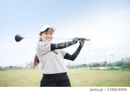 ゴルフ練習場でドライバーショットをスウィングする若い笑顔の女性イメージ ナイスショット ゴルフ練習場でドライバーショットをスウィングする若い笑顔の女性イメージ ナイスショット 139824994