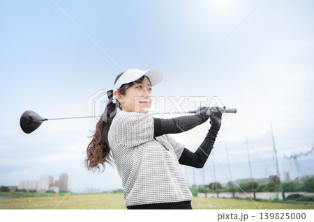 ゴルフ練習場でドライバーショットをスウィングする若い笑顔の女性イメージ ナイスショット ゴルフ練習場でドライバーショットをスウィングする若い笑顔の女性イメージ ナイスショット 139825000