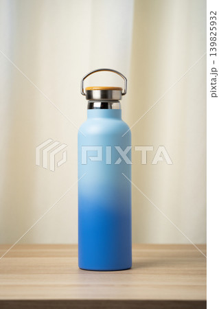 A sleek blue insulated stainless steel water bottle with bamboo cap, designed for reusable everyday hydration and travel. Minimalist matte ombre gradient finish and durable build make it ideal for gym 139825932