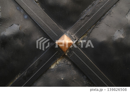 A black gate has metal bars in a cross shape with a copper pyramid 139826508