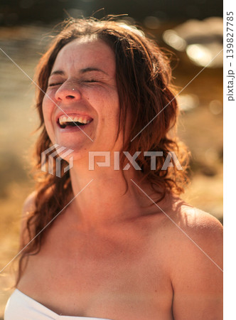 Happy brunette woman enjoying golden hour light by the water in nature Happy brunette woman enjoying golden hour light by the water in nature 139827785
