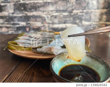 サワラとアオリイカの昆布締め。新鮮な刺身を昆布で包んで熟成させた料理。アオリイカに醤油をつけて食べる サワラとアオリイカの昆布締め。新鮮な刺身を昆布で包んで熟成させた料理。アオリイカに醤油をつけて食べる 139828382