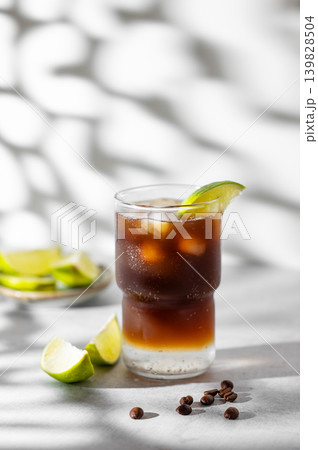 Cold Coffee Tonic Drink With Lime and Ice on light background with shadows Cold Coffee Tonic Drink With Lime and Ice on light background with shadows 139828504