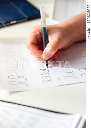 Physical over Digital concept. Woman training calligraphy at desk. Handwriting improves concentration and conceptual understanding better than digital notes. Perfect tool for mental clarity. Focus Physical over Digital concept. Woman training calligraphy at desk. Handwriting improves concentration and conceptual understanding better than digital notes. Perfect tool for mental clarity. Focus 139828675