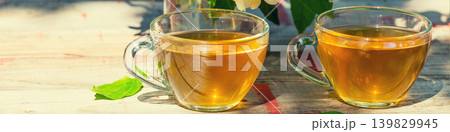 Two cups of green tea with jasmine flowers on grunge wooden table outdoors Two cups of green tea with jasmine flowers on grunge wooden table outdoors 139829945
