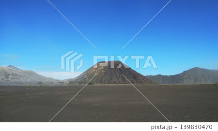Wide angle view of Mount Batok volcano cone in the center of black sand desert at Bromo Tengger Semeru Indonesia Wide angle view of Mount Batok volcano cone in the center of black sand desert at Bromo Tengger Semeru Indonesia 139830470