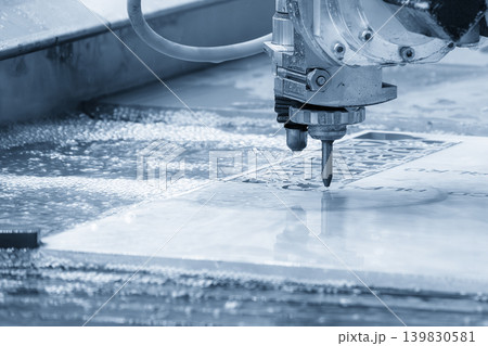 High-pressure abrasive water jet cutting machine processing an aluminum plate in a blue-toned industrial scene. High-pressure abrasive water jet cutting machine processing an aluminum plate in a blue-toned industrial scene. 139830581