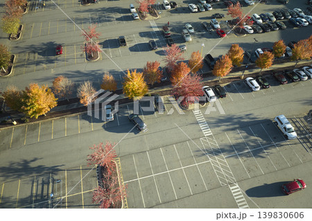 Aerial view of many colorful cars parked on parking lot with lines and markings for parking places and directions. Place for vehicles in front of a strip mall plaza Aerial view of many colorful cars parked on parking lot with lines and markings for parking places and directions. Place for vehicles in front of a strip mall plaza 139830606