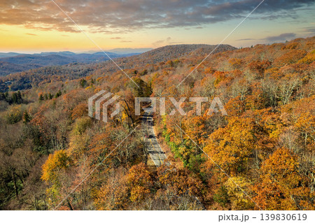 Blue Ridge Parkway road in autumn woods of Appalachian mountains at sunset with yellow and orange canopies in colorful forest. Road trip driving in wild nature in fall season Blue Ridge Parkway road in autumn woods of Appalachian mountains at sunset with yellow and orange canopies in colorful forest. Road trip driving in wild nature in fall season 139830619