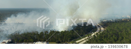Fire department firetrucks extinguishing wildfire burning severely in Florida jungle woods. Emergency service vehicles trying to put down flames in forest Fire department firetrucks extinguishing wildfire burning severely in Florida jungle woods. Emergency service vehicles trying to put down flames in forest 139830678
