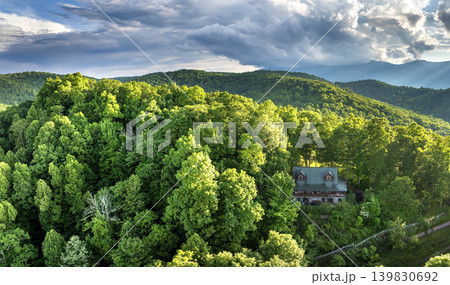 Old wooden house on hillside near in North Carolina Blue Ridge Mountains. Beautiful nature landscape. Green woods illuminated with bright setting sun. Aerial view of colorful sunset in wild mountains 139830692