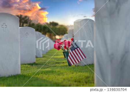 Military burial headstones. Cemetery with rows of white tomb stones with flowers and USA flags on green grass. Memorial Day concept 139830704